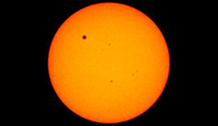 Venus appears as a small dot in the upper left as it passes between the sun and Earth in 2012. Image: NASA