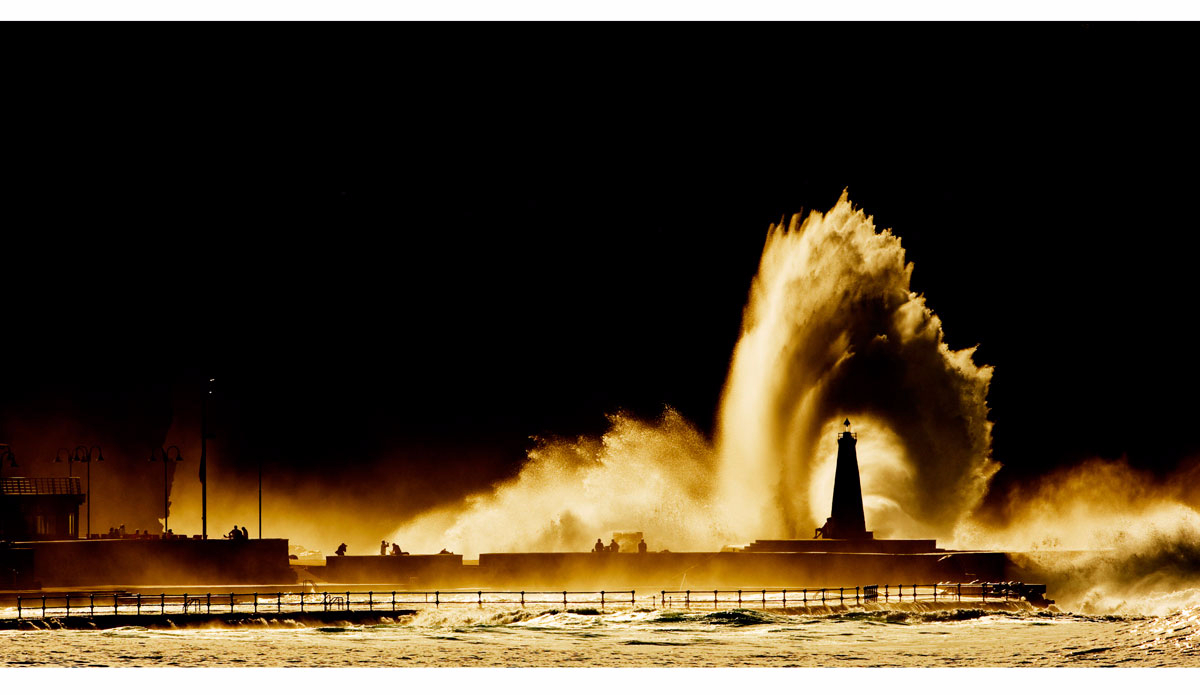 This picture was shot coming back from a tow in-session in the Canary Islands. After the surf we’ve pulled the ski at the port and decided to have lunch at the restaurant next to the launch pad. Sitting at the window of the restaurant, I spotted this wave hitting the lighthouse on the other side of the bay. I took my 600mm lens, went out and nailed that photo in the first five minutes. The beer was still cold when I got back to the restaurant. Photo: <a href=\"https://instagram.com/alexlaurelphotographie\">Alex Laurel</a>