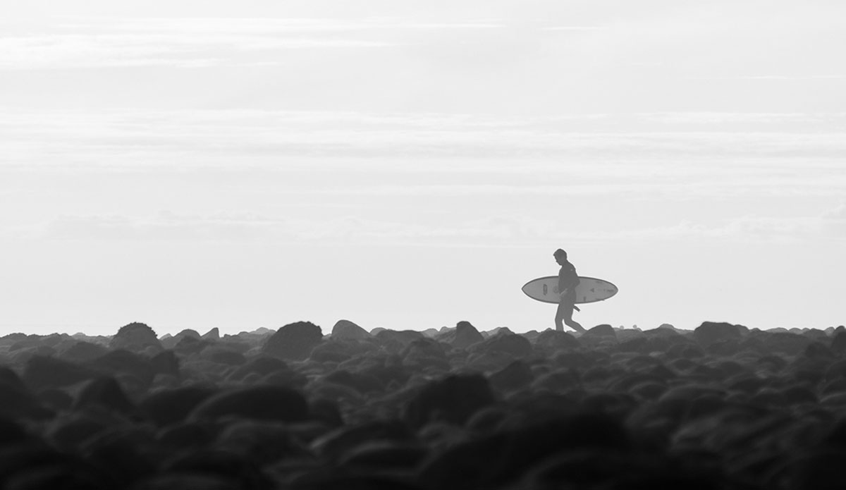 An unknown surfer heading out but first has to dance around a field of rocks at The Queen of the Coast, Rincon. Photo: <a href=\"http://www.kincaidcliffordphotography.com/\"> Brian Clifford</a>