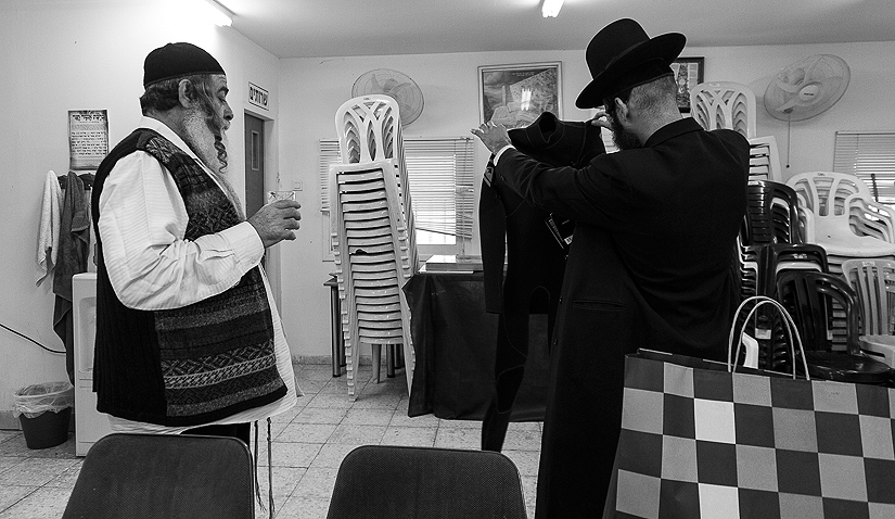 Meir showing off his new wetsuit to a friend in \"Orut Hatorah\" synagogue in Bat Yam.