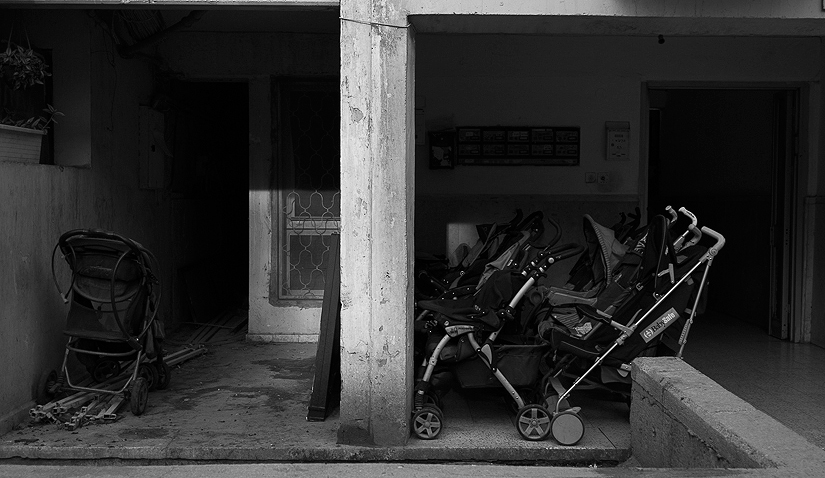 Baby strollers in the entrance of Meir\'s building. In the Jewish orthodox society, it is a
blessing to have many children.