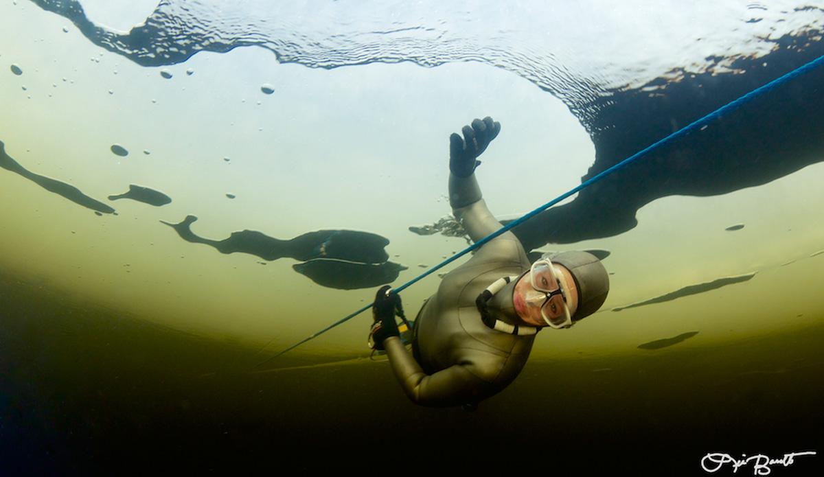 Freediver Chloe Villaume pauses between ice holes. Photo: <a href=\"http://liabarrettphotography.com/\" target=_blank>Lia Barrett</a>