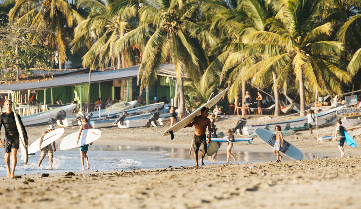 A typical scene of fishing boats, coconut laden palms, and surfers walking up the beach after long rides down the point. Photo Keoki Saguibo