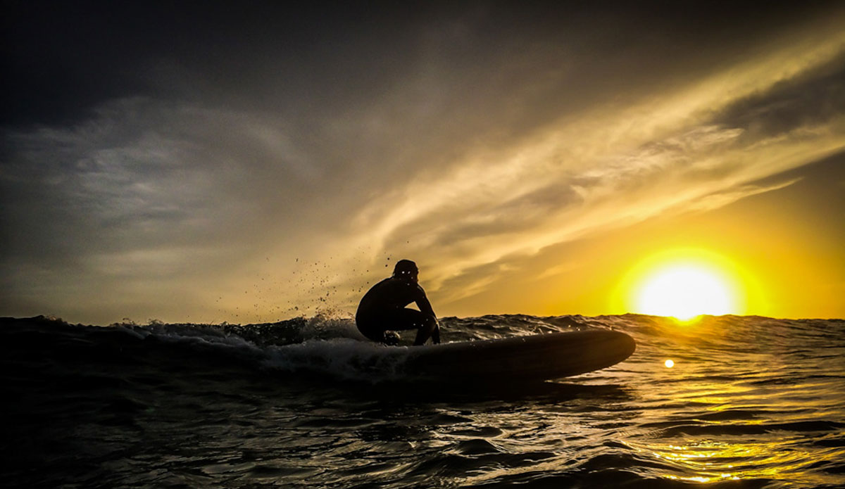 Surfer Bob Lavender making a smooth bottom turn, clouds from an incoming cold front, and a setting sun dipping behind the wave combine for a dramatic shot. Photo: <a href=\"https://richbrooksphotography.squarespace.com/\"> Rich Brooks</a>