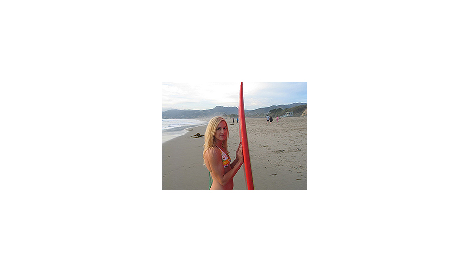 Lynn on the beach with her board.