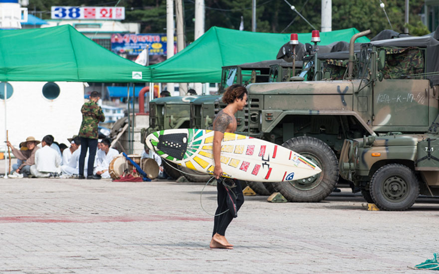 Local surfer Dong-hoon Han heads out through army vehicles during the last typhoon season which brought great waves to the area. Photo: <a href=\"http://www.shannonaston.com/\" target=_blank>Shannon Aston</a>.