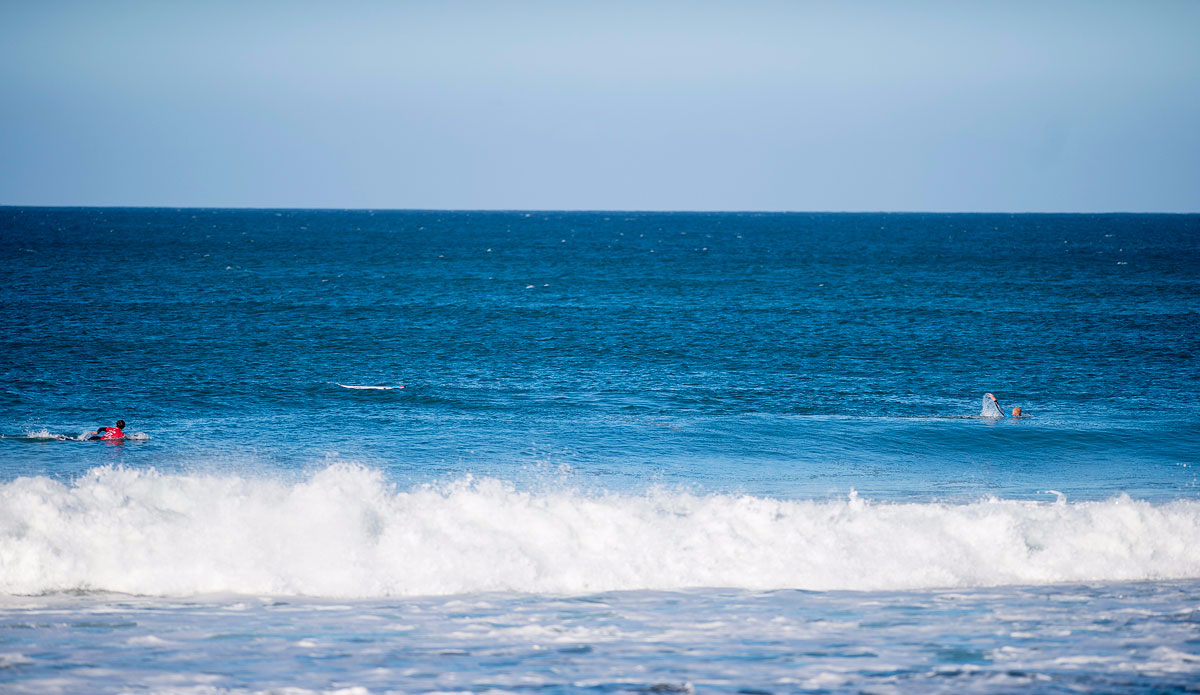 Mick Fanning of Australia (pictured blue) raises his hand and swims away from his board after being attacked by a shark in the Final of the JBay Open as his fellow competitor Julian Wilson (in red) swims to help him on Sunday July 19, 2015. Screengrab: <a href=\"http://www.worldsurfleague.com/\">WSL</a>

