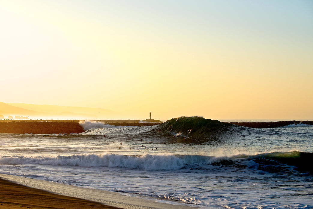 A massive, refracted peak towers over the assembled crowd of locals during this late season dawn session at the Wedge. Photo: Benjamin Ginsberg / Driftwood Photography Studios