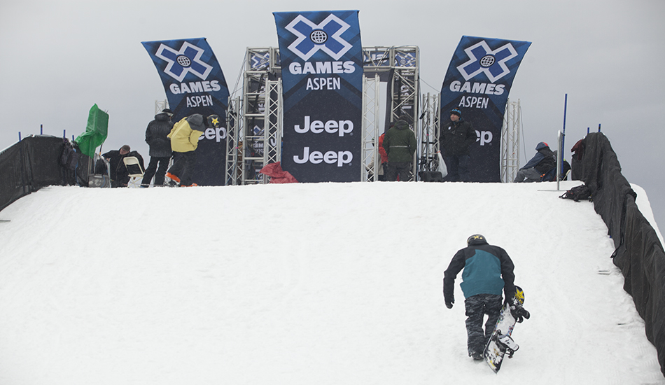 The party doesn\'t start for the athletes until it\'s done and dusted. A snowboarder makes the long trudge to the top of the Slopestyle course during practice. 