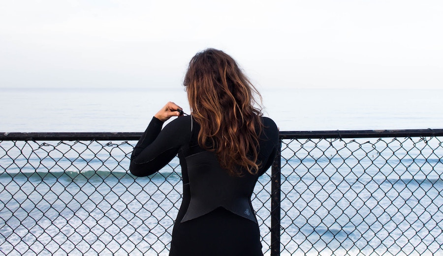 Woman suiting up in wetsuit in Encinitas.