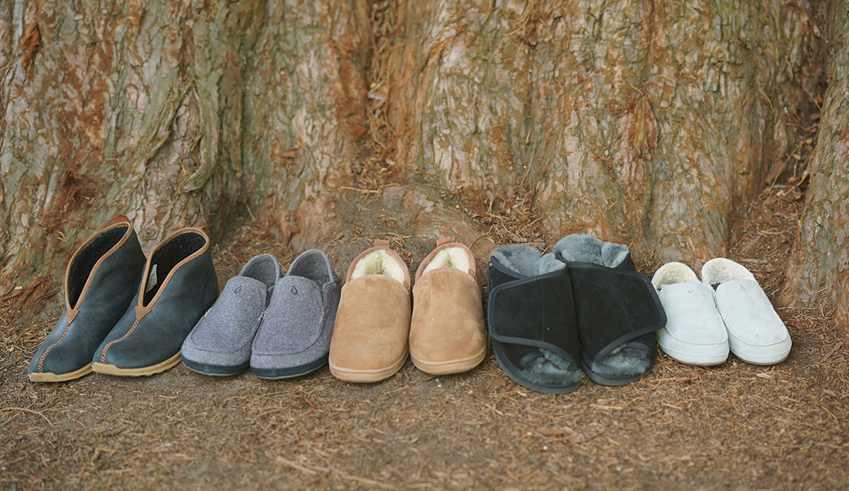 A picture of some of the slippers we tested for the best camping slippers review, lined up underneath a tree.