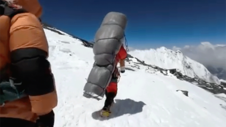 Gelje Sherpa carries a climber down Mt. Everest