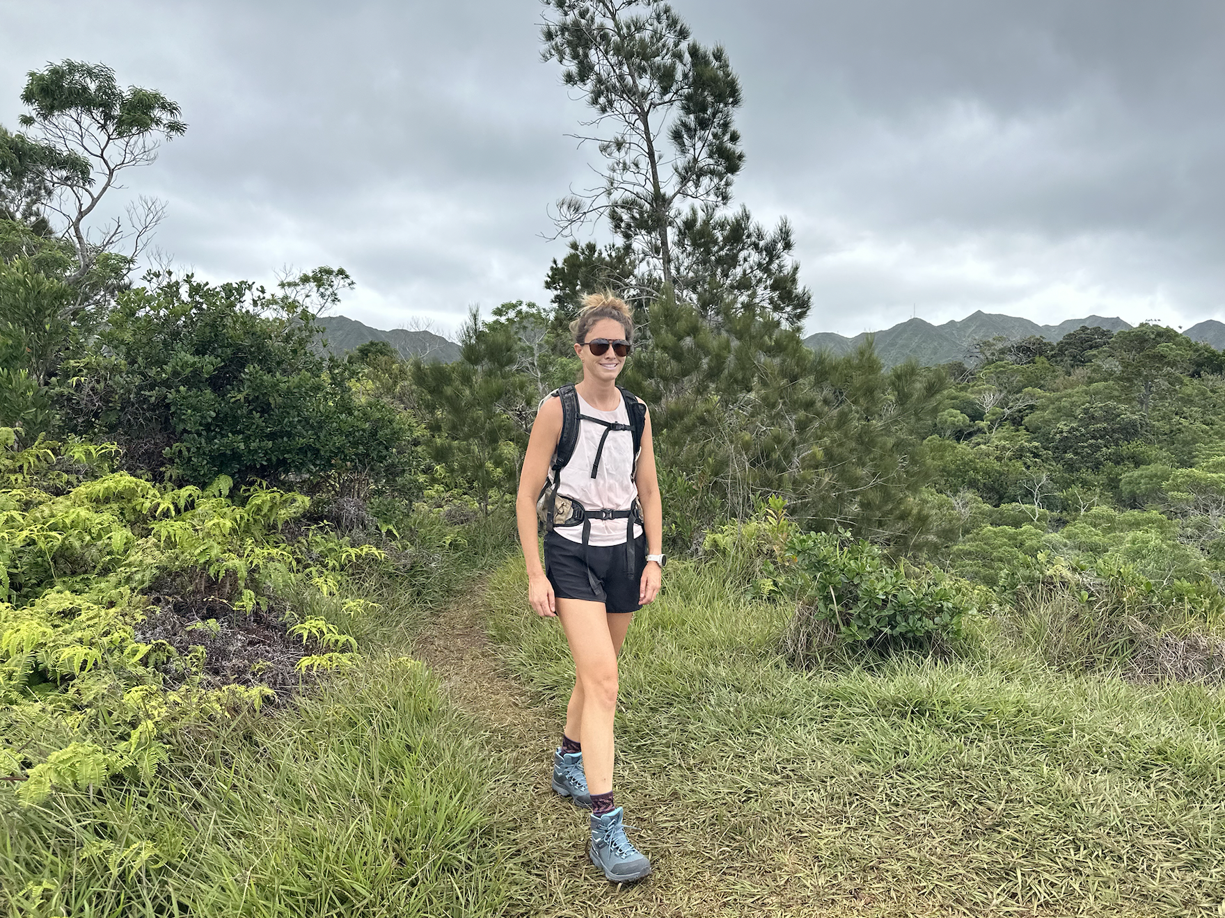 a woman hiking in a green area wearing a pair of hiking boots