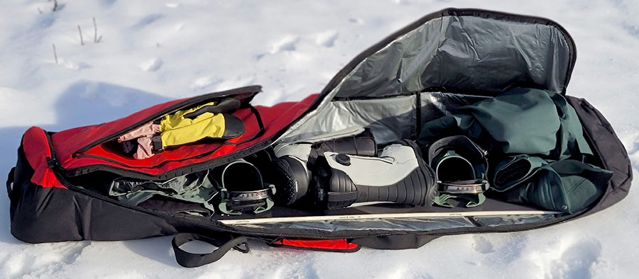 the element equipment snowboard bag loaded with gear, laying on the snow