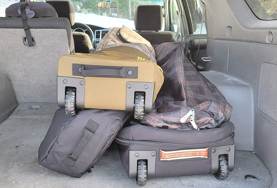 four snowboard bags stacked in the back of a SUV