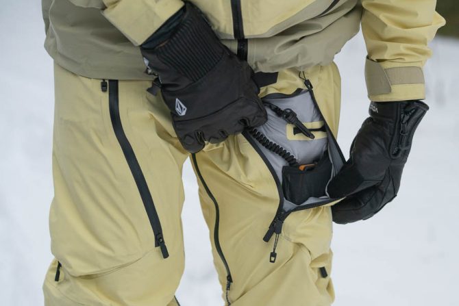 showing the pocket of the burton kalausi bib pants and how they hold a transceiver with a dedicated loop