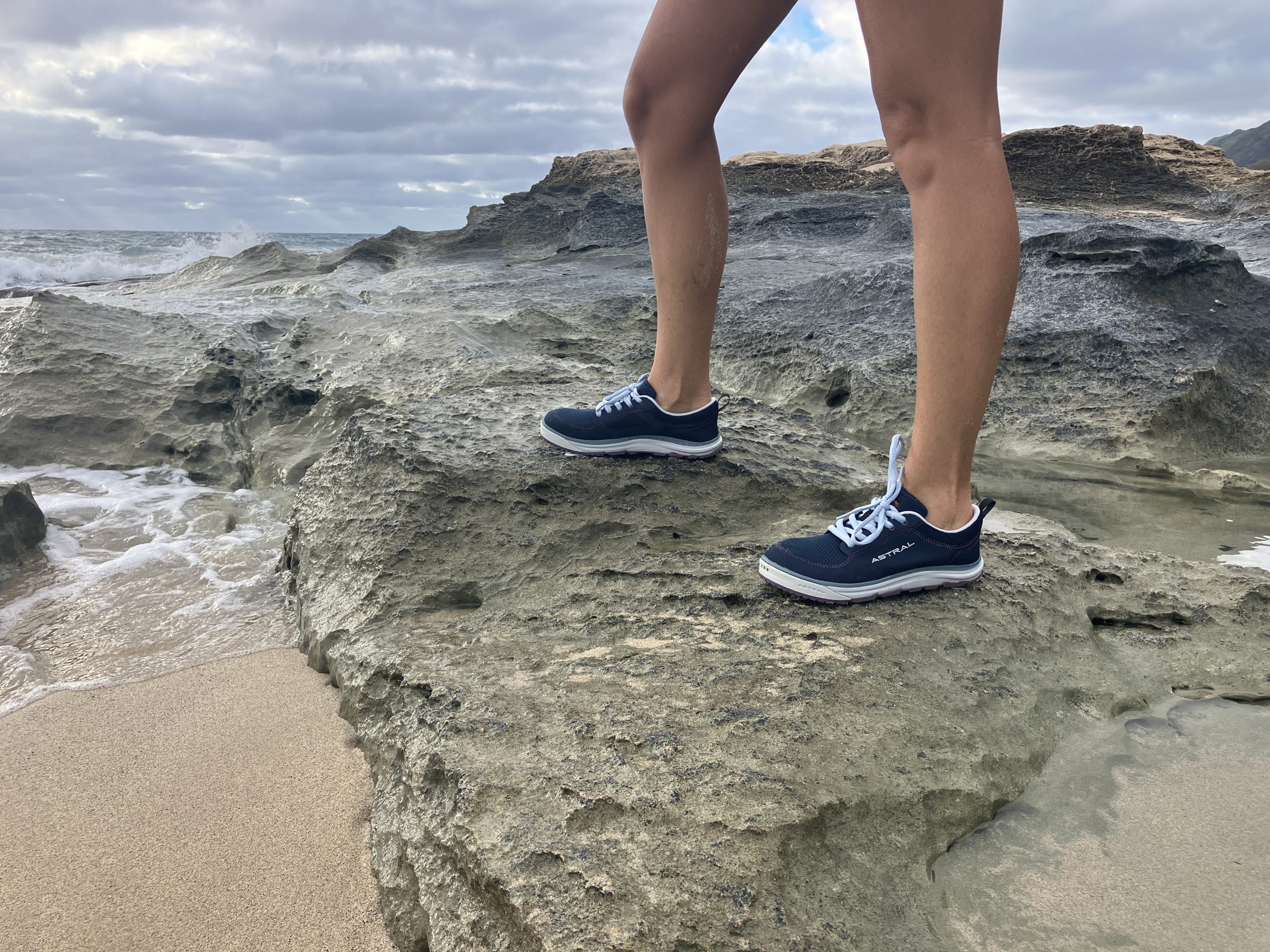 wearing astral brewess 2.0 water shoes on a rock at the beach