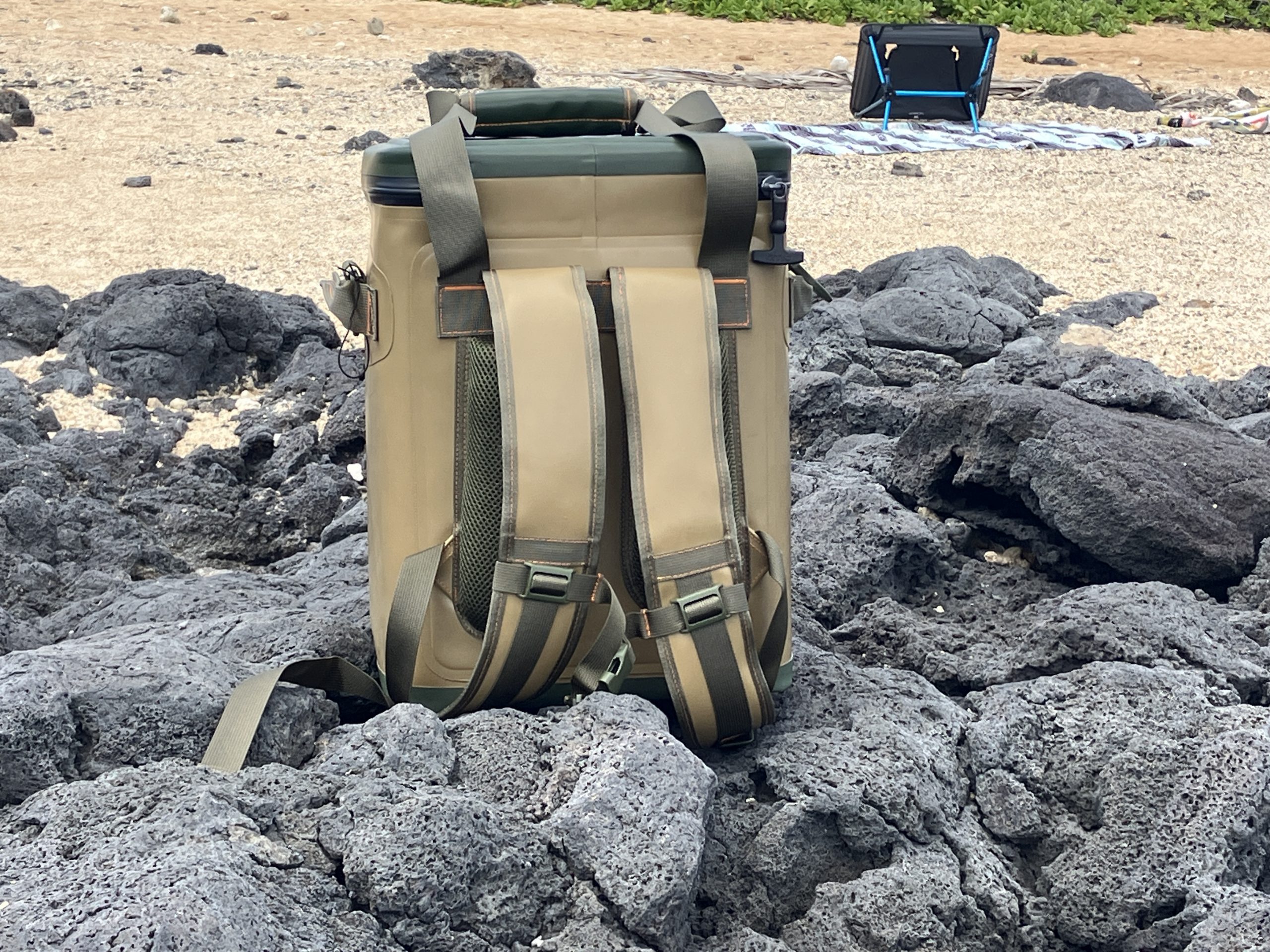 the backside of an RTIC Backpack Cooler on rocks at the beach