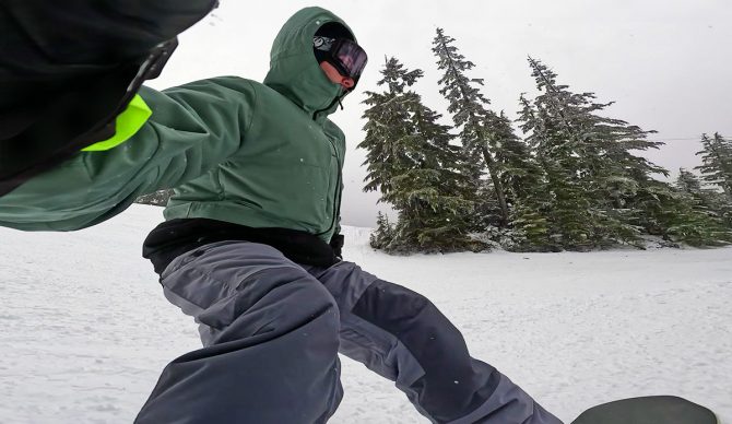 A snowboarder rides down a mountain taking a selfie