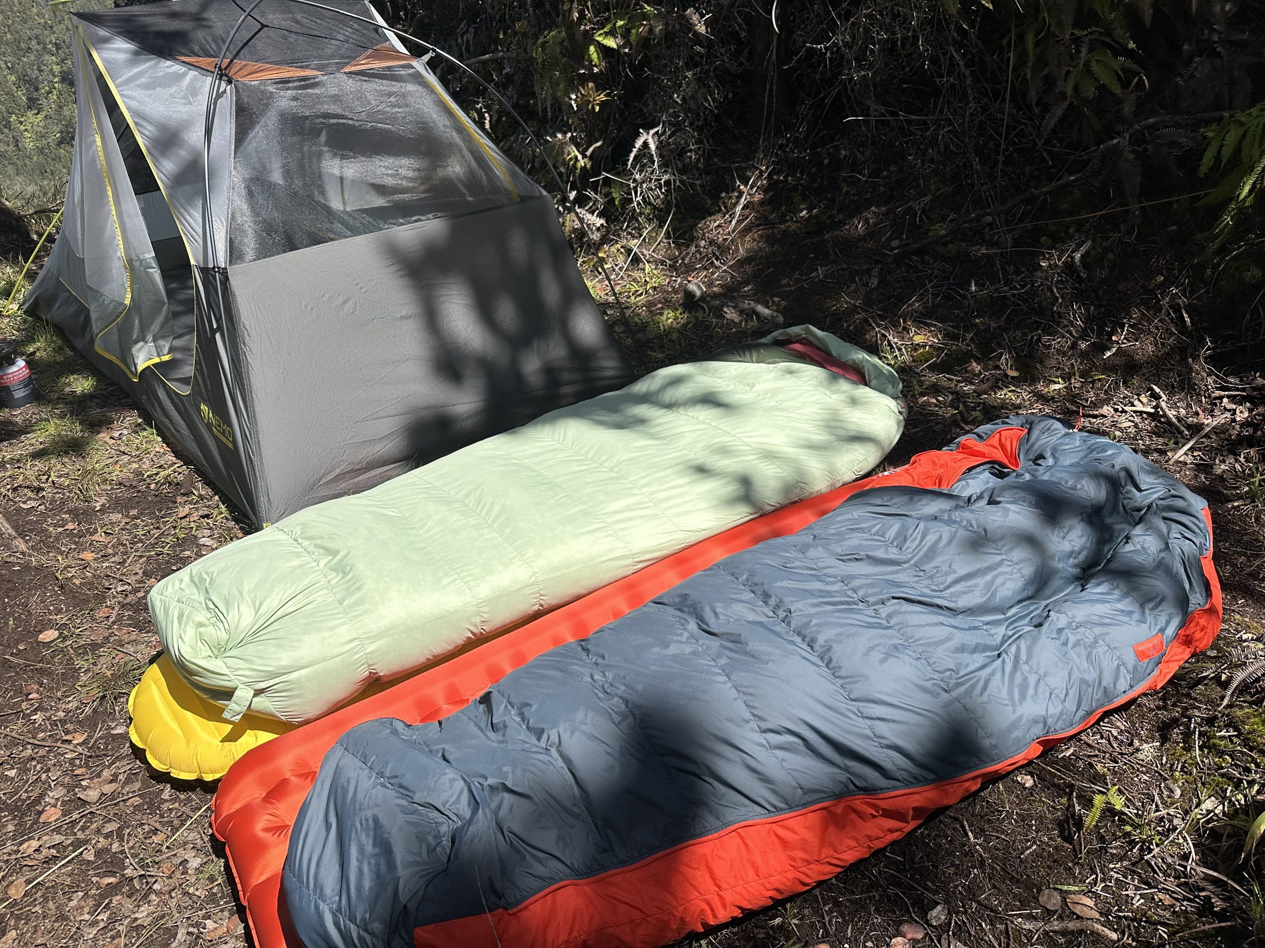 two backpacking sleeping bags on sleeping pads outside