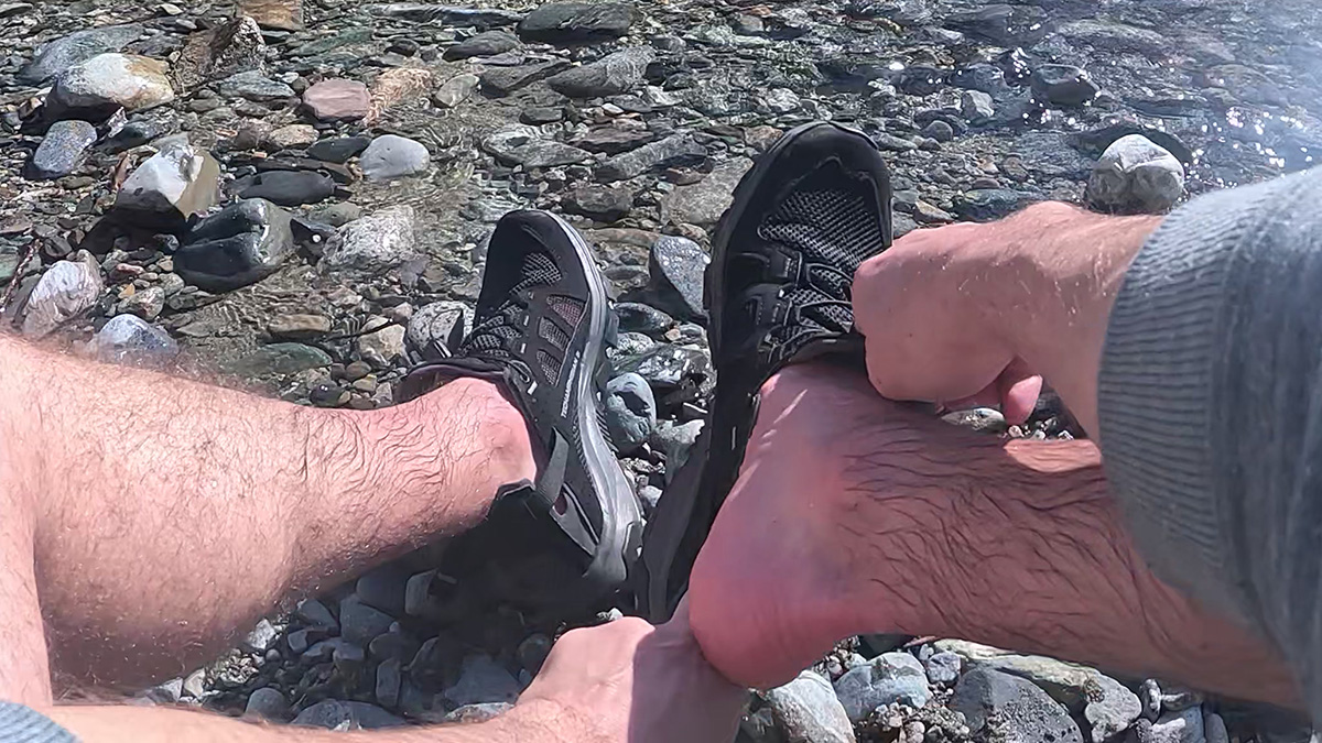 Putting on the Salomon Techamphibian 5 water shoes by a river