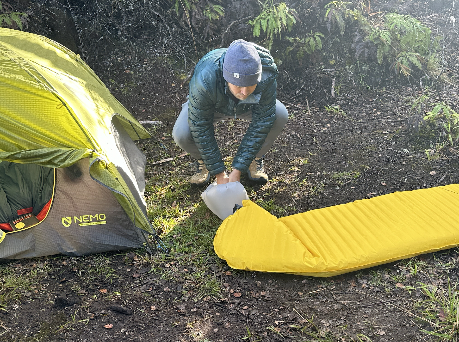 a man inflating one of the backpacking sleeping pads we tested