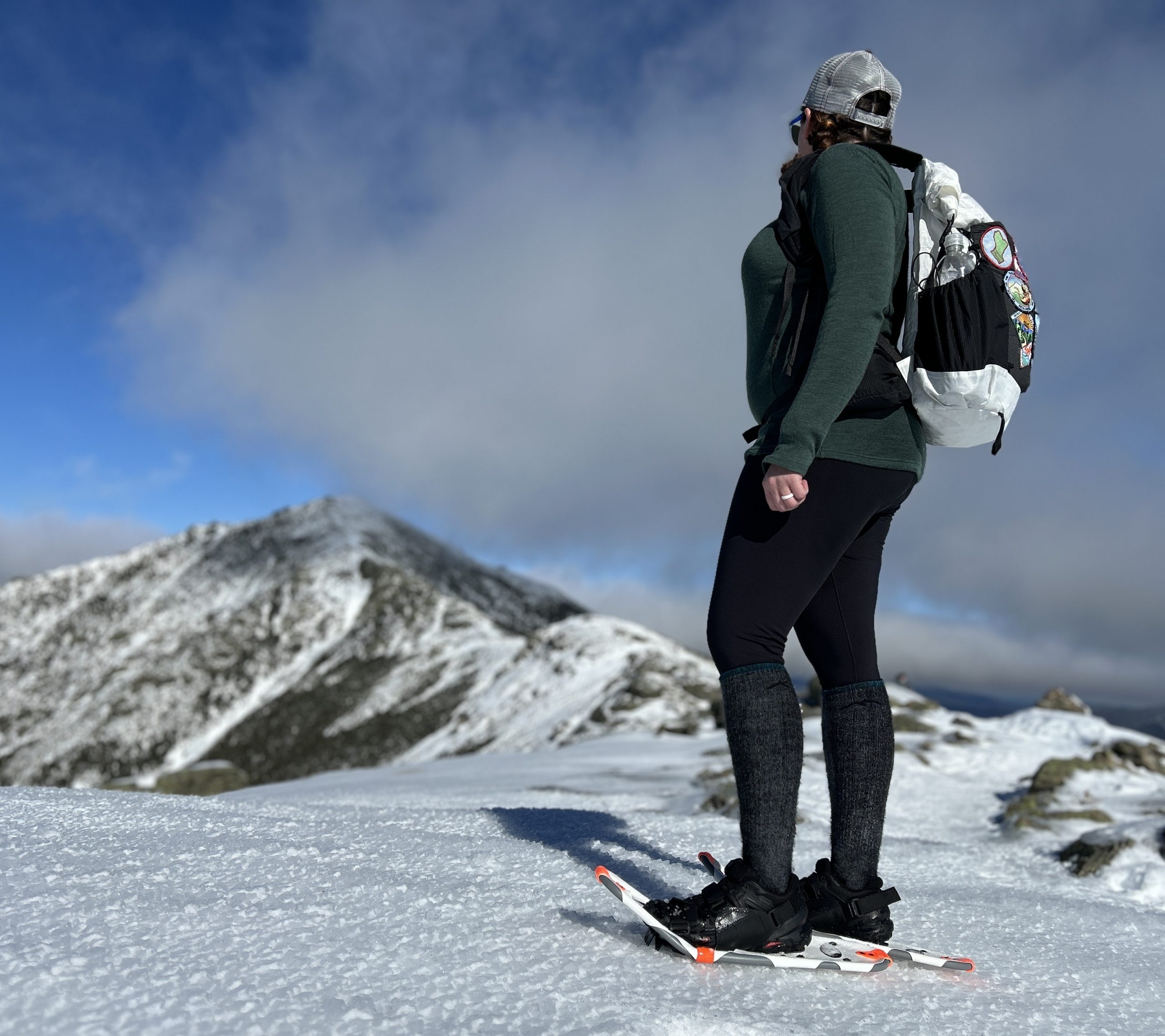 A woman wearing Dion 121 snowshoes on a snowy ridge in New Hampshire