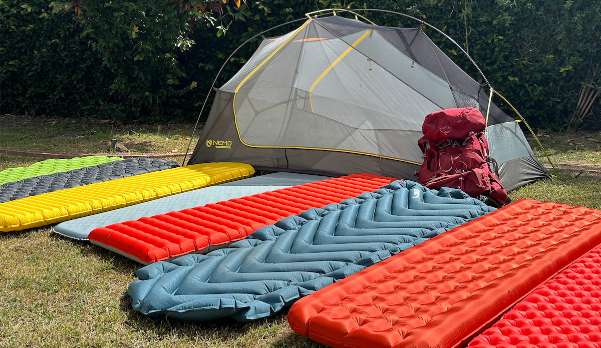 a row of backpacking sleeping pads lined up in front of a tent 