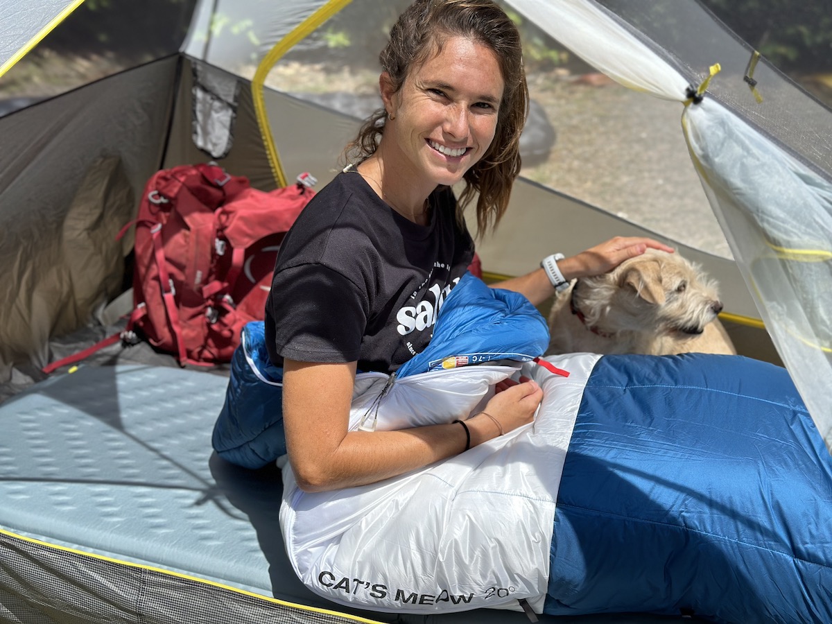 a woman sitting in a sleeping bag in a tent