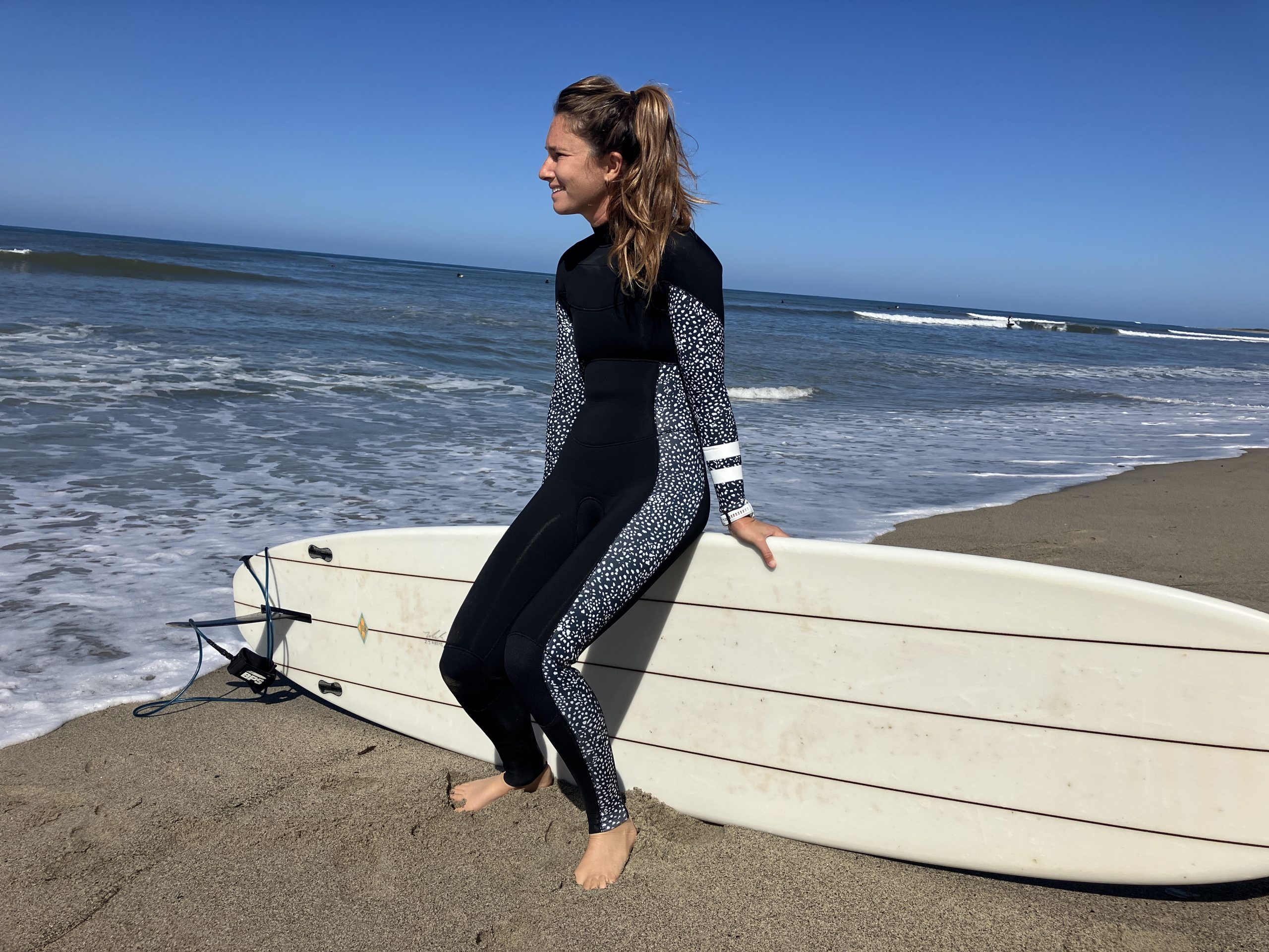 a woman sitting on a surfboard wearing a wetsuit