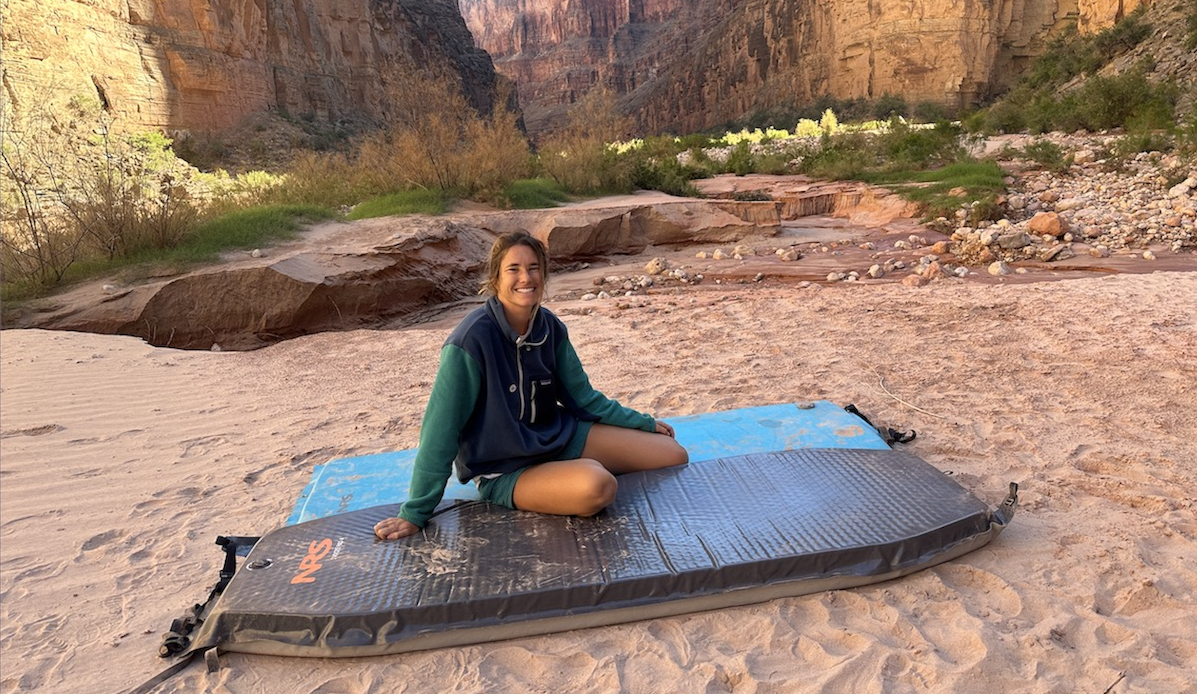 a woman wearing a fleece jacket sitting on a sleeping pad