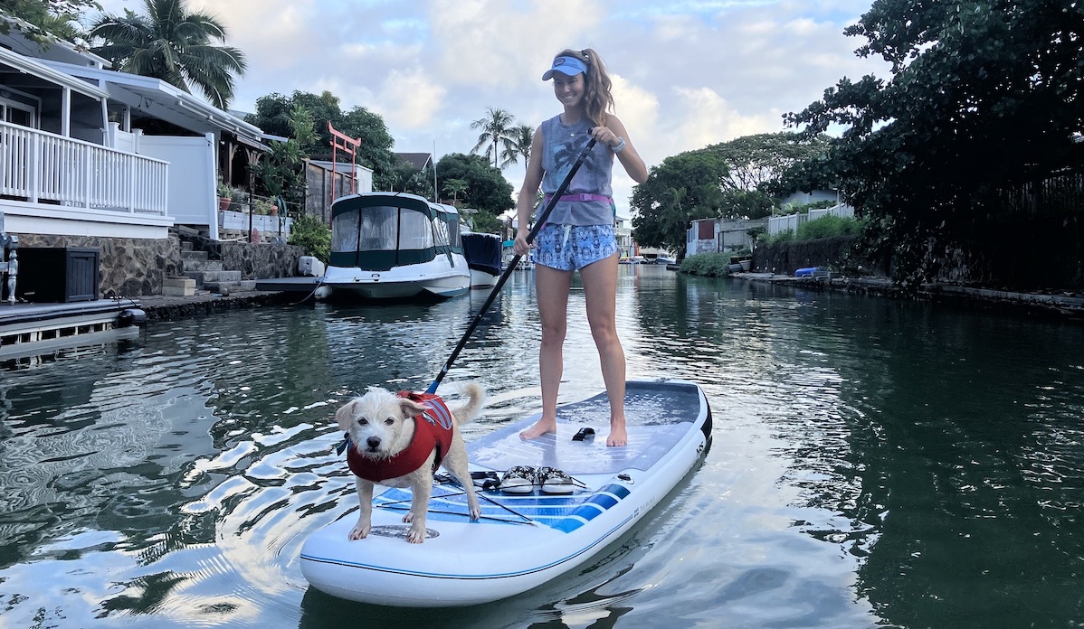 a woman stand up paddling with her dog