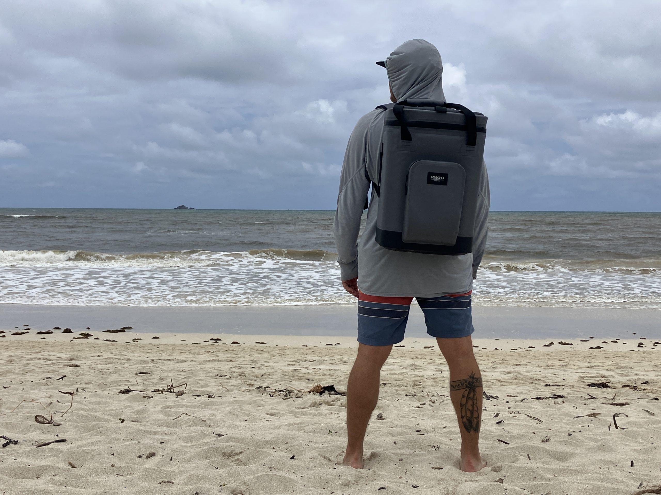 a man wearing a backpack cooler at the beach