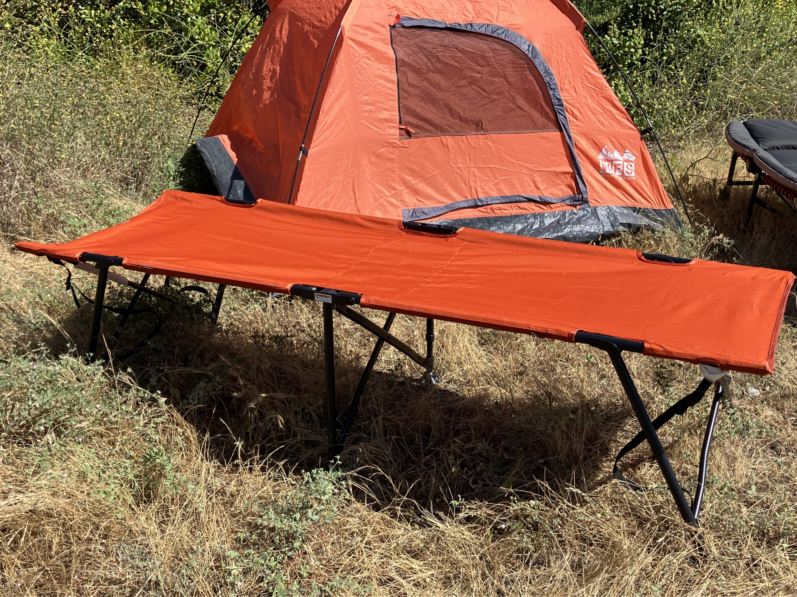 a camping cots in front of a tent 