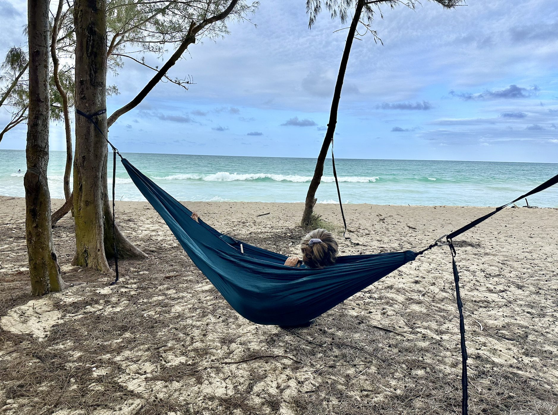 a woman laying in a hammock at the beach