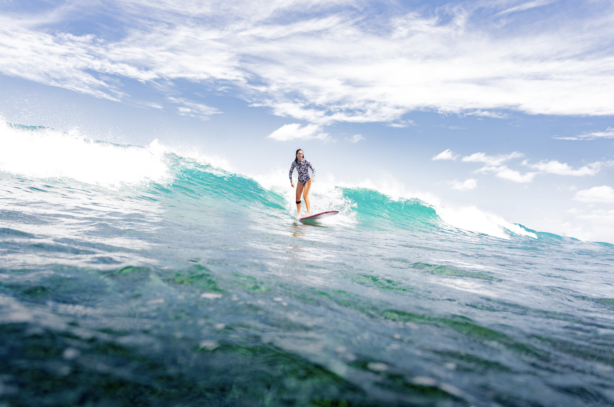 a womam surfing in the tropics wearing a surf suits