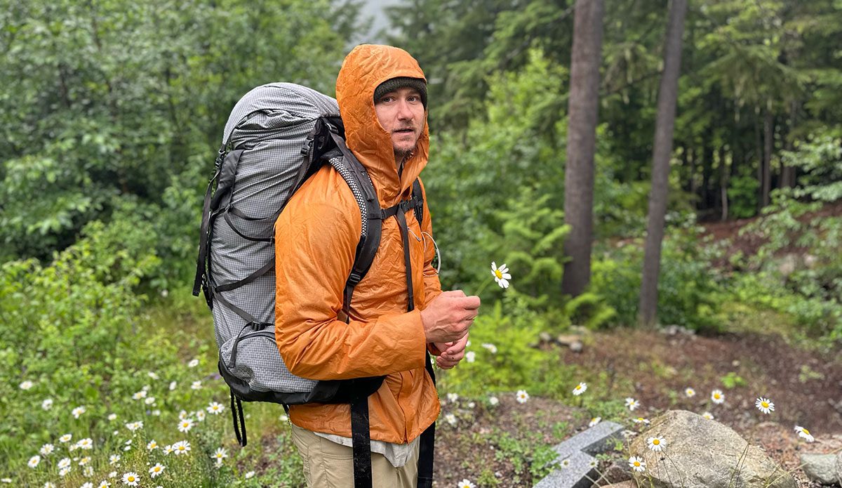 a hiker with a backpack holding a flower