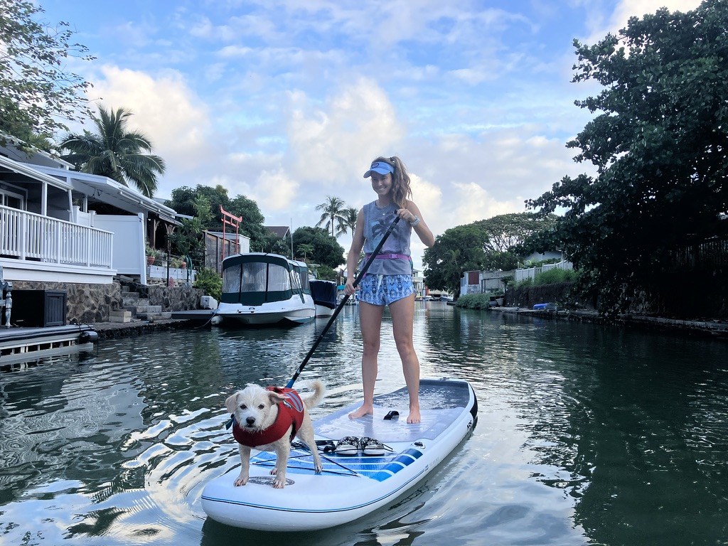 a woman and a dog paddle boarding