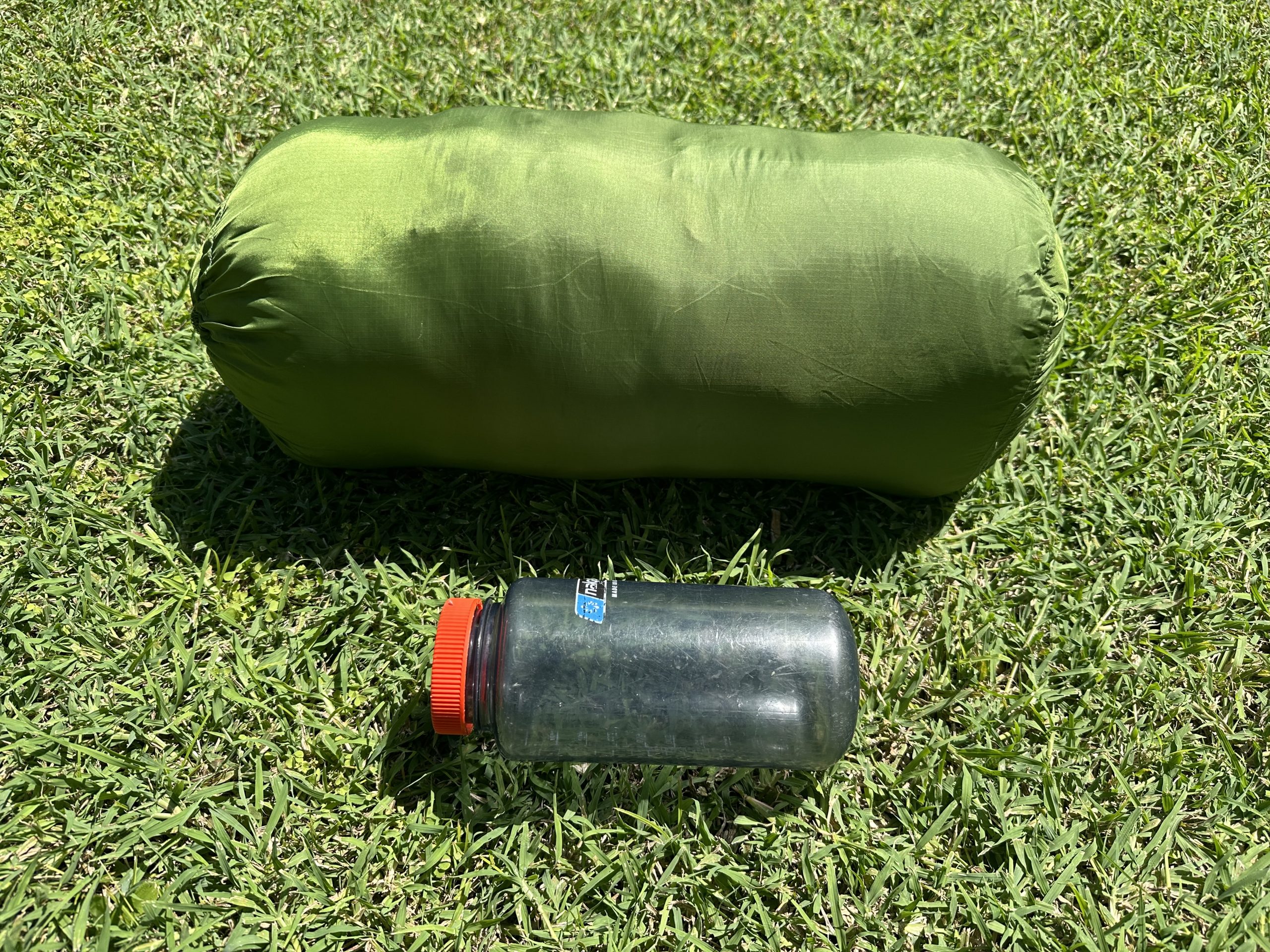 big agnes sleeping bag packed up next to a water bottle