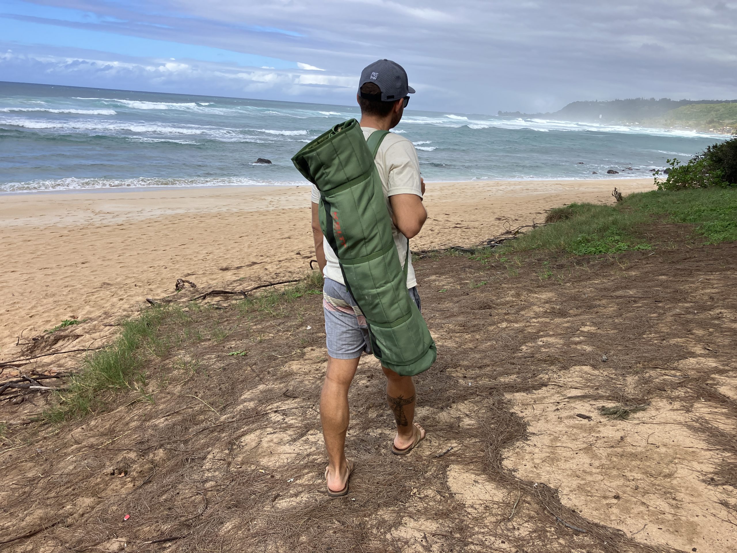 a man walking with a folded up camping chair