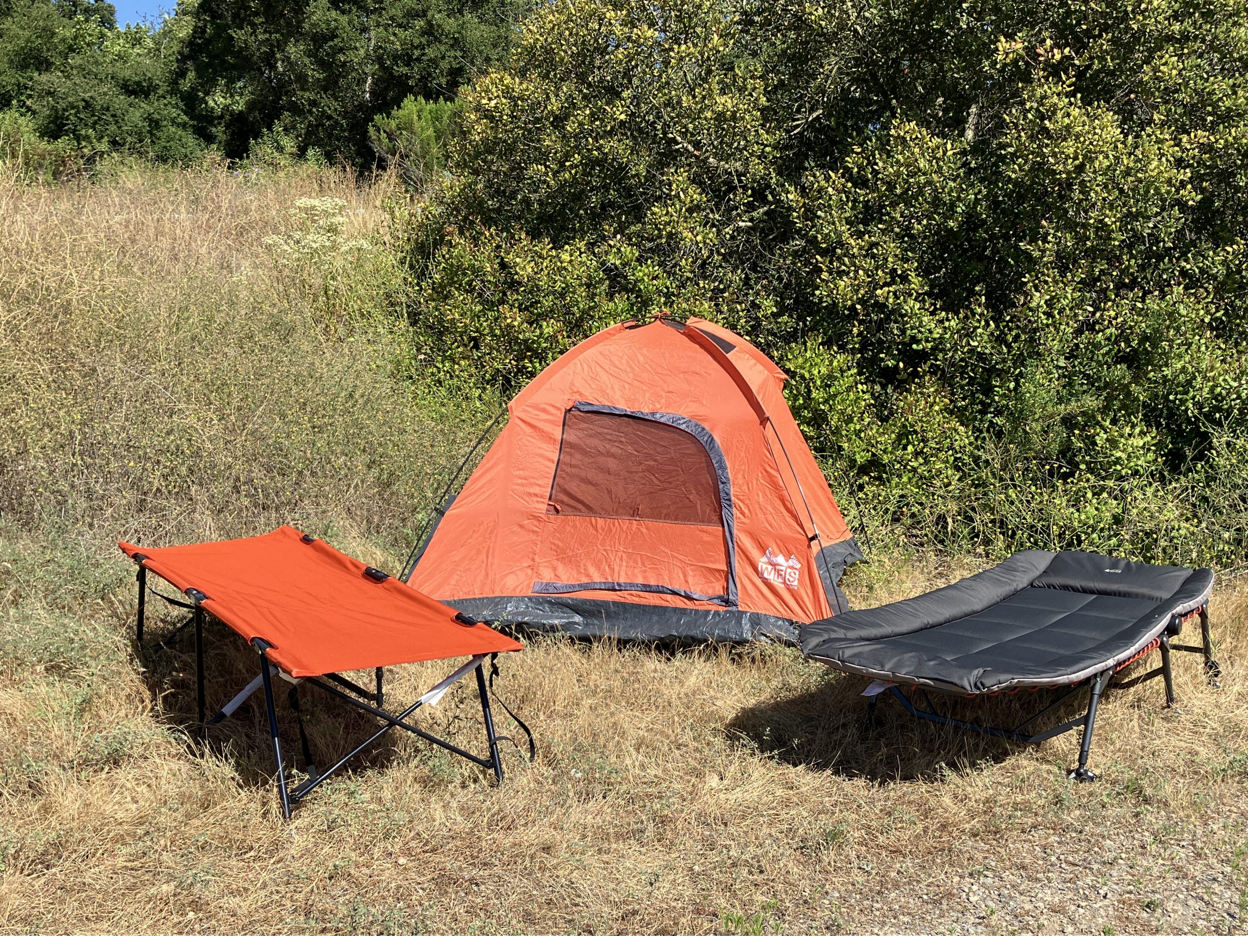 two camping cots set up in front of a tent