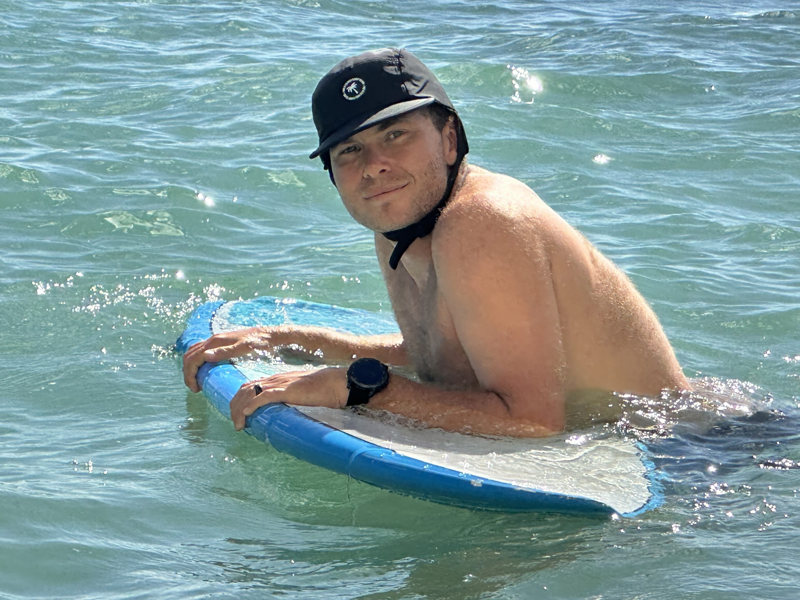 a man in the water wearing a surf hat