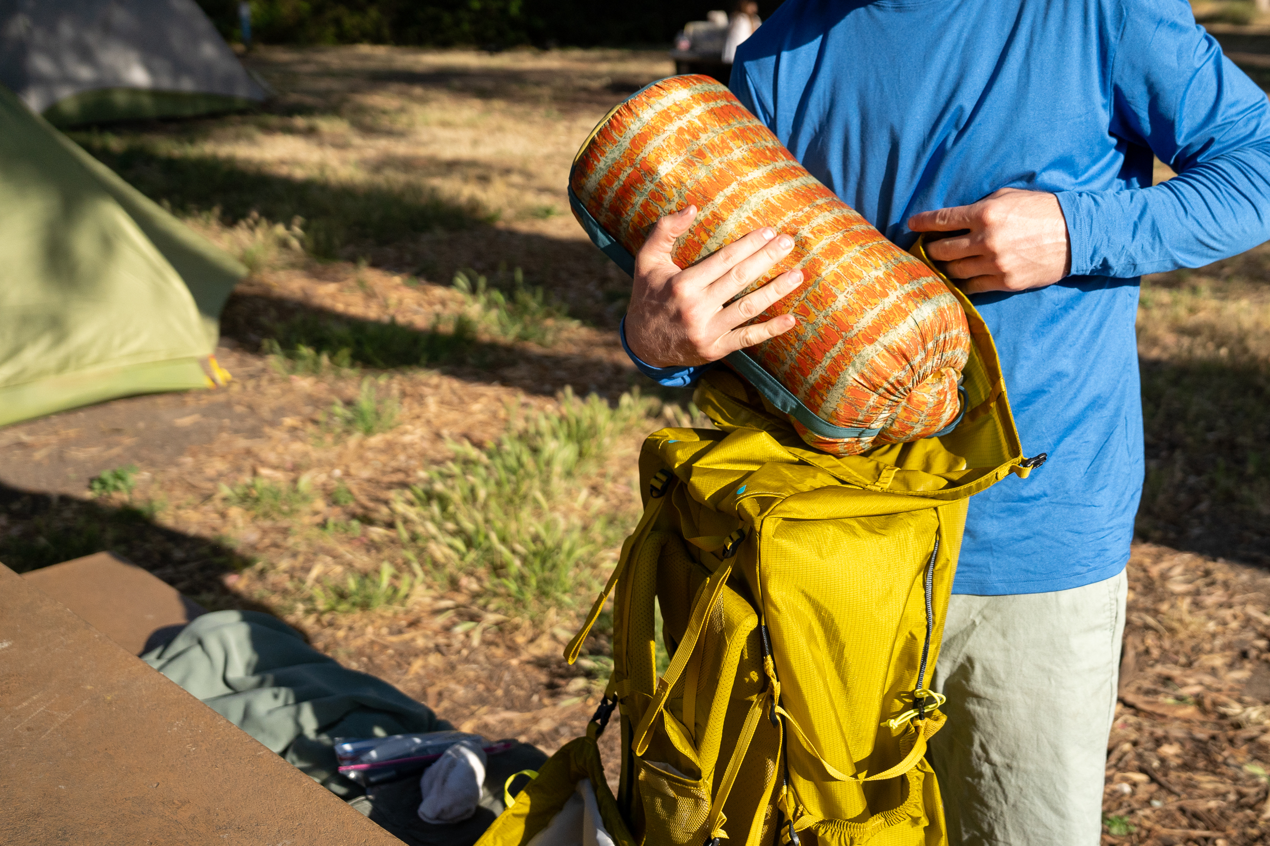 a man loading a sleeping bag into a backpack