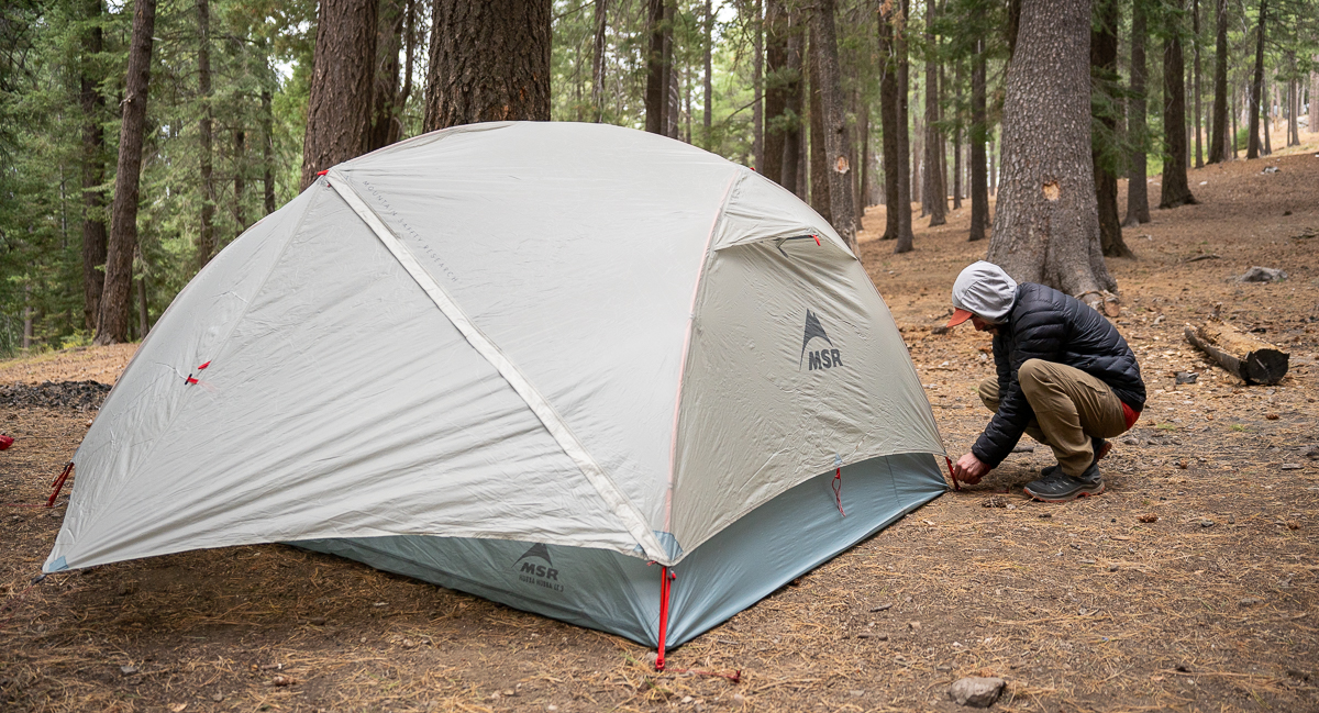 man staking out backpacking tent