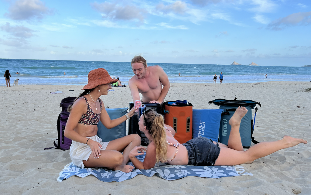 people enjoying drinks on the beach by coolers