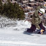 man snowboarding and slinging snow