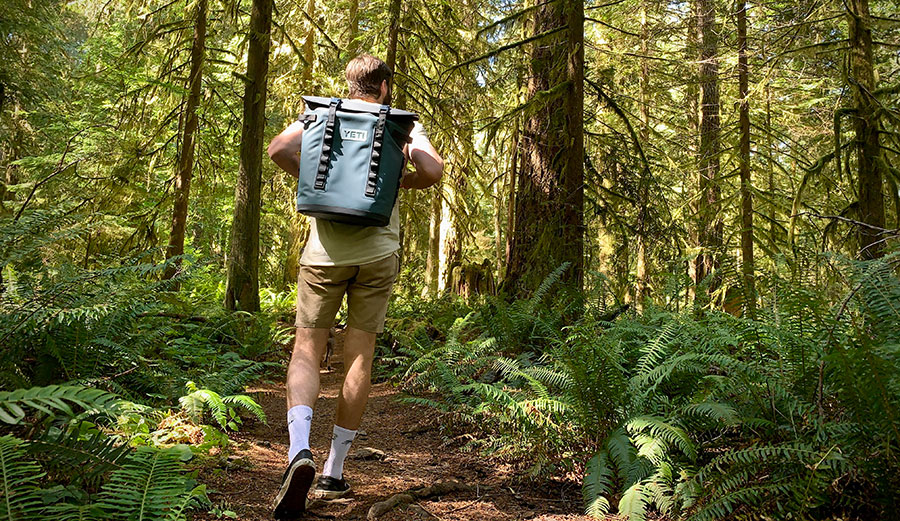 man walking with backpack cooler