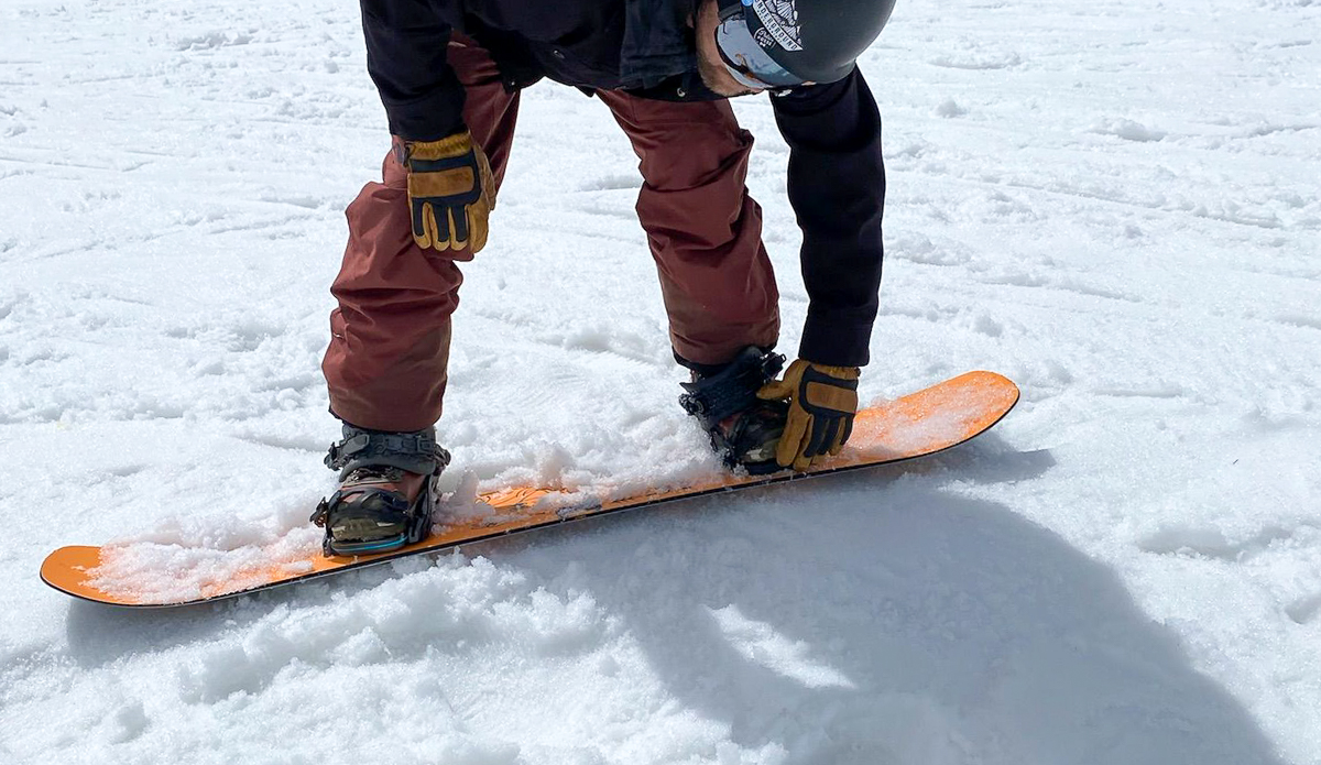 man strapping in snowboard bindings