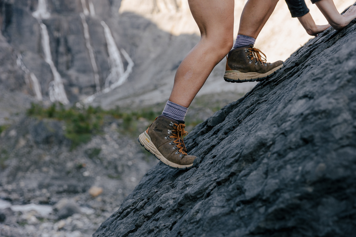 woman scrambling up rocks in hiking boots