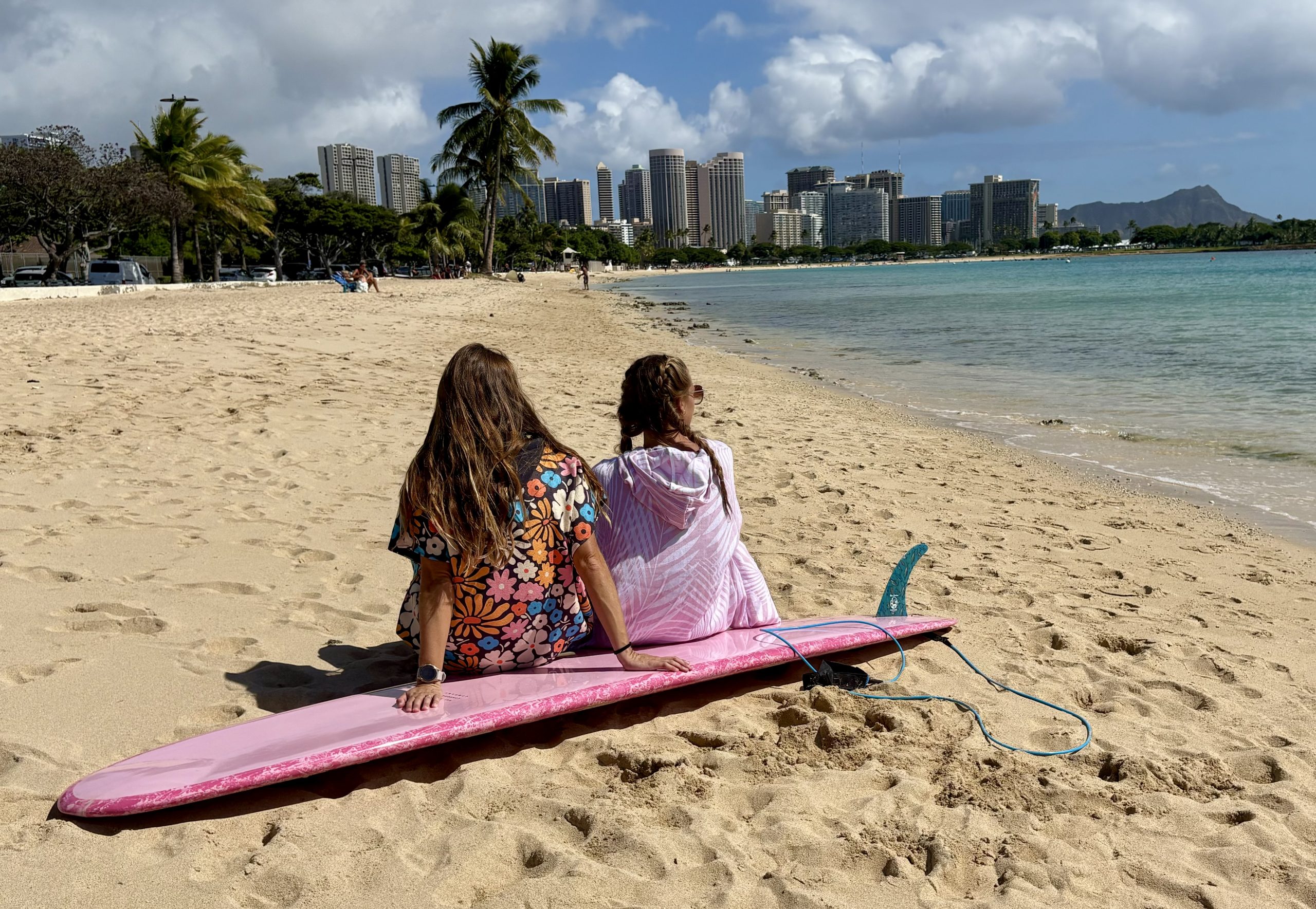 girls sitting on the beach in surf ponchos